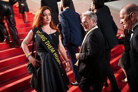 A person wears a sash with "Bring them home" during 'The Shrouds' premiere